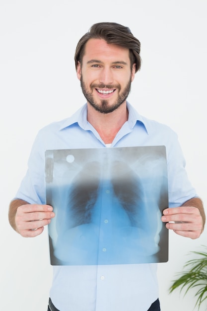 Portrait of a smiling young man holding lung xray