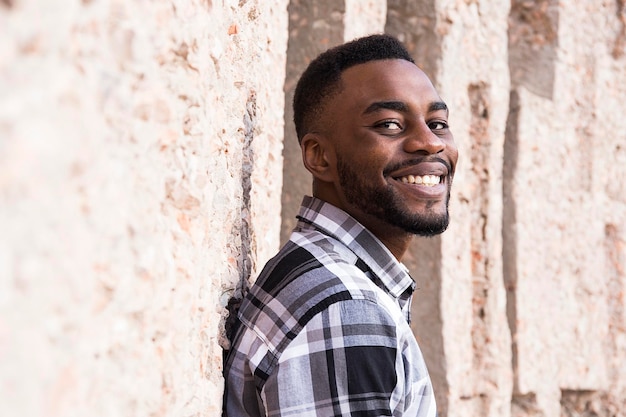 Photo portrait of smiling young man leaning against wall