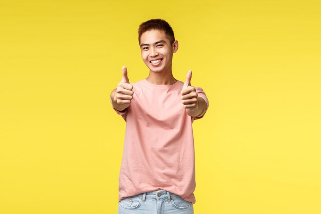 Portrait of smiling young man standing against yellow background