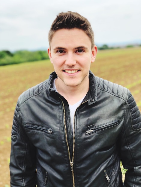 Portrait of smiling young man standing on field