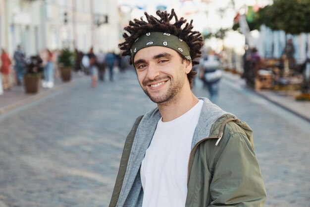 Foto ritratto di un giovane sorridente in piedi per strada