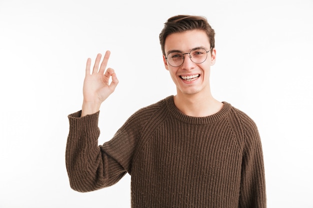 Portrait of a smiling young man in sweater showing ok