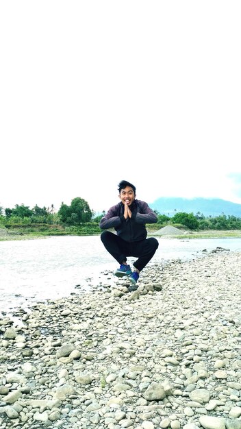 Portrait of smiling young man with hand clasped at riverbank