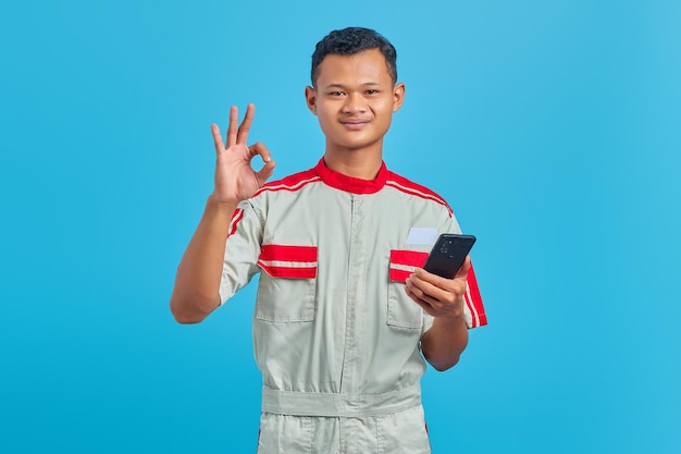 Portrait of smiling young mechanic making okay gesture and showing approval symbol