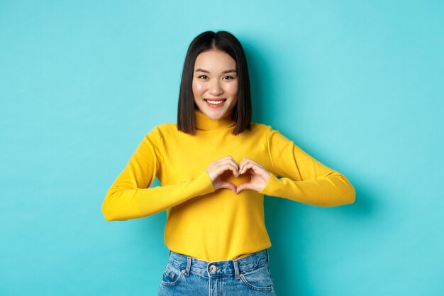 Photo portrait of a smiling young woman against blue background