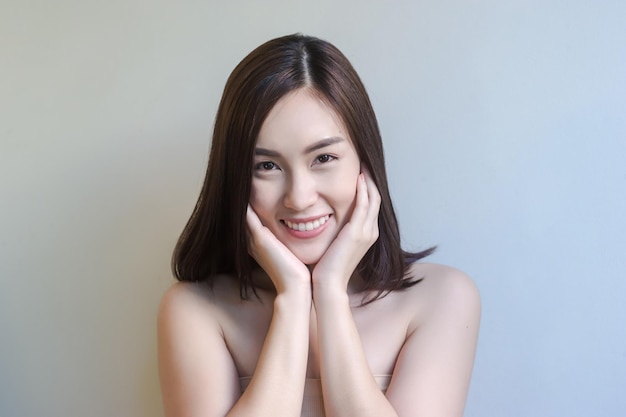 灰色の背景に笑顔の若い女性の肖像画