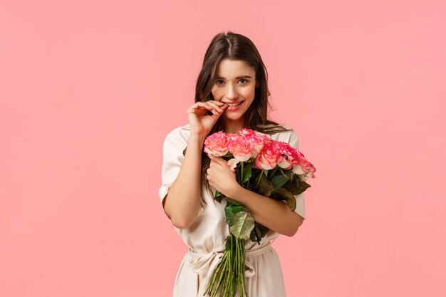 Portrait of a smiling young woman against pink background