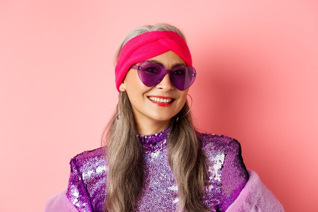 Photo portrait of smiling young woman against pink background