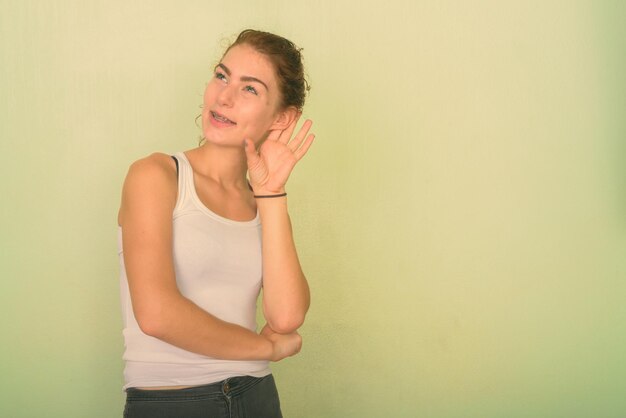 Portrait of smiling young woman against wall