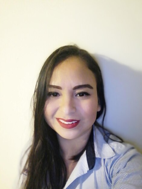 Portrait of a smiling young woman against wall