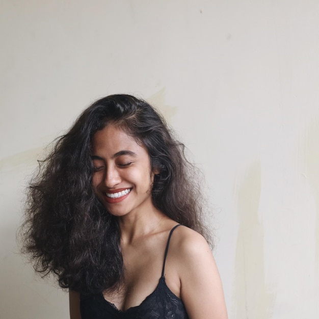 Portrait of a smiling young woman against wall