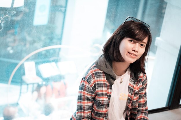 Photo portrait of smiling young woman against window