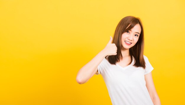 Portrait of a smiling young woman against yellow background