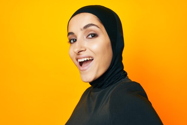 Portrait of smiling young woman against yellow background