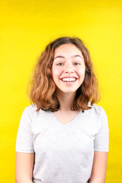 Photo portrait of smiling young woman against yellow background