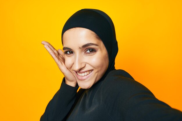 Portrait of smiling young woman against yellow background