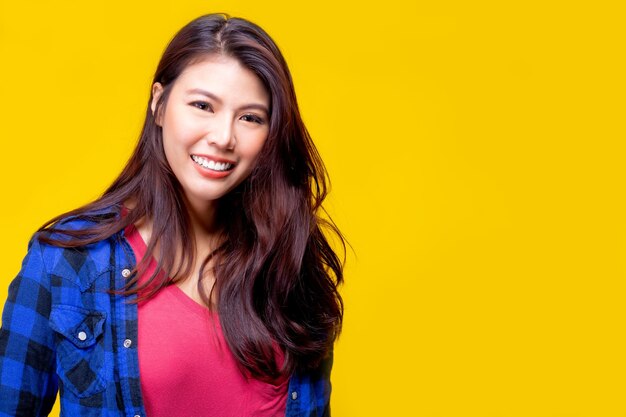 Portrait of smiling young woman against yellow background