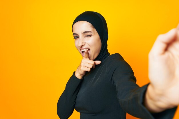 Portrait of smiling young woman against yellow background