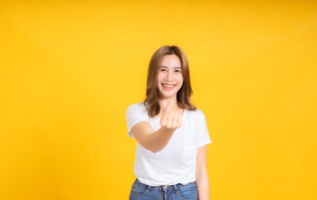 Portrait of smiling young woman against yellow background