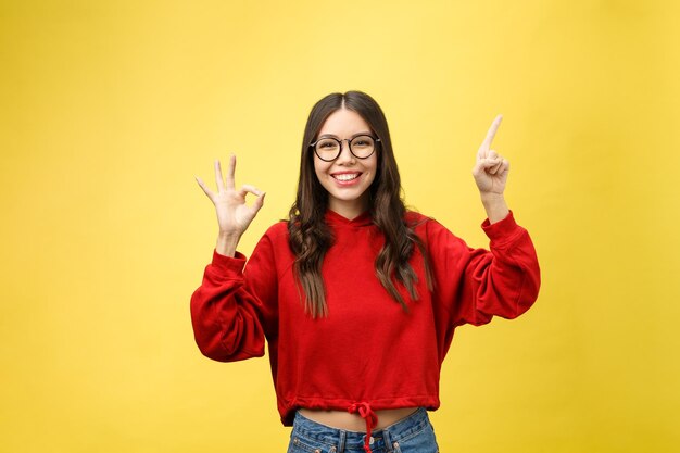 Portrait of smiling young woman against yellow background