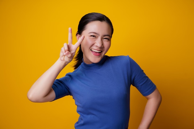 Portrait of smiling young woman against yellow background