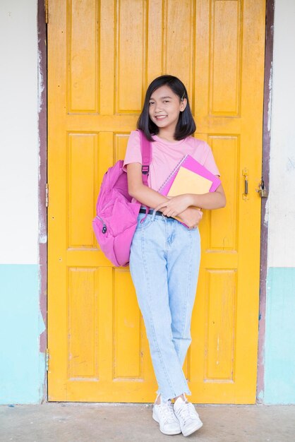 Portrait of a smiling young woman against yellow door