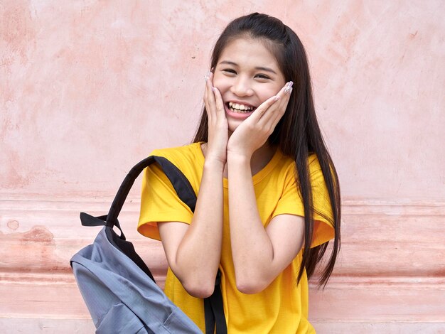 Portrait of smiling young woman against yellow wall