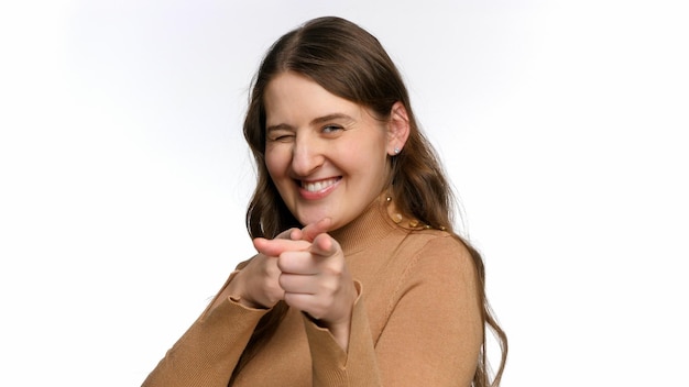 Photo portrait of smiling young woman aiming in you with fingers concept of success winning and victory