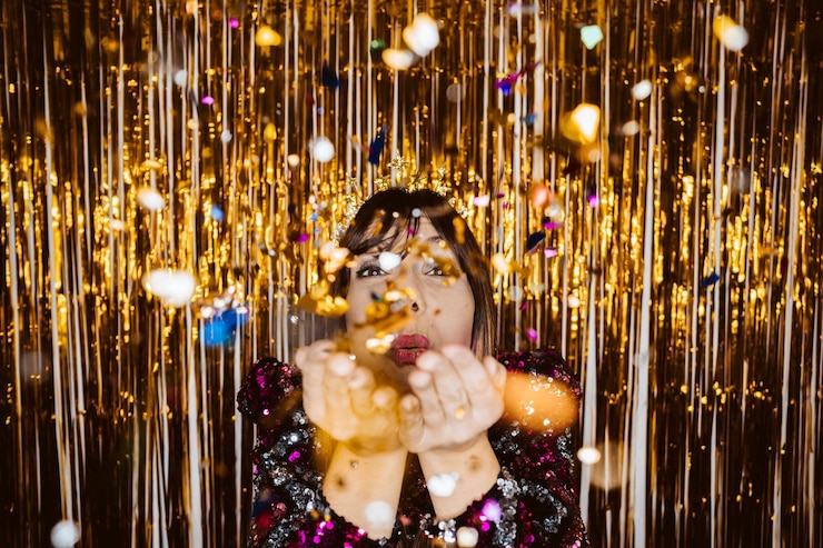 फोटो portrait of smiling young woman blowing glitter against colored background