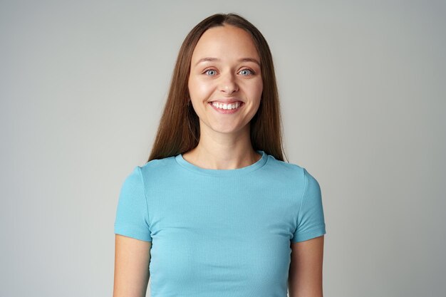 Portrait of smiling young woman in blue tshirt on gray background