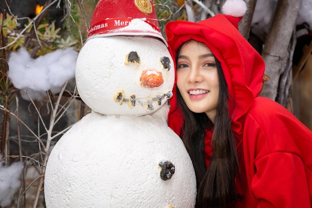 Photo portrait of smiling young woman by snowman