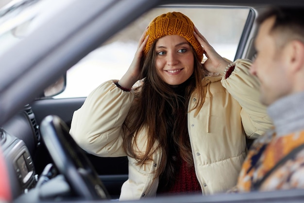 Portrait of smiling young woman in car with boyfriend ready for winter getaway together