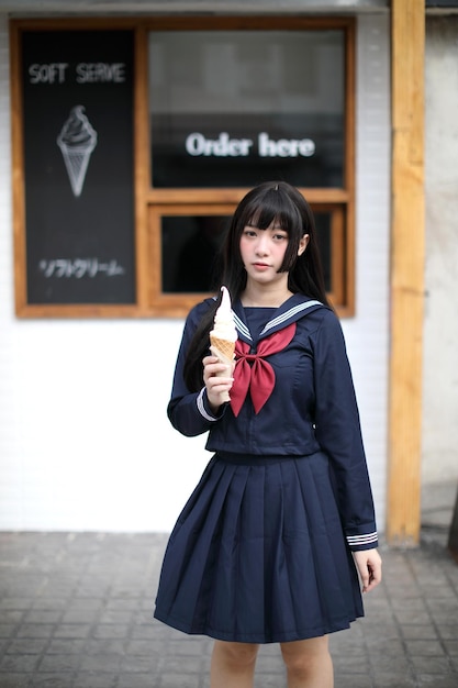 Photo portrait of smiling young woman eating ice cream standing outdoors