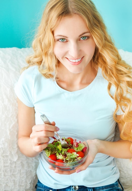 Foto ritratto di una giovane donna sorridente che mangia l'insalata a casa