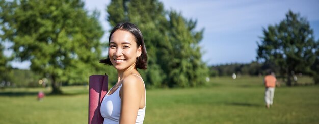 Portrait of smiling young woman exercising on field