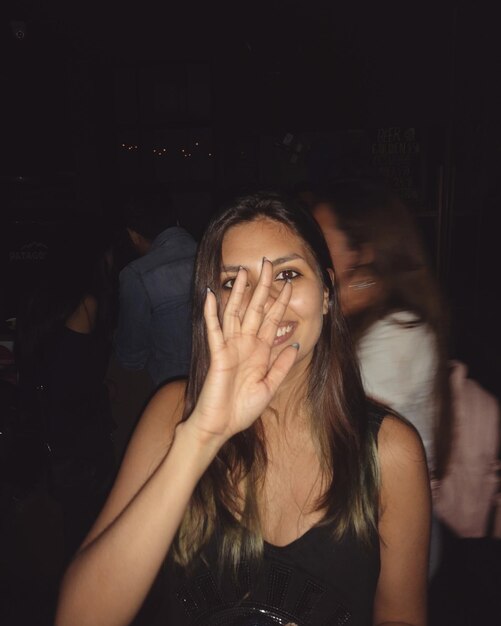 Photo portrait of smiling young woman gesturing at night