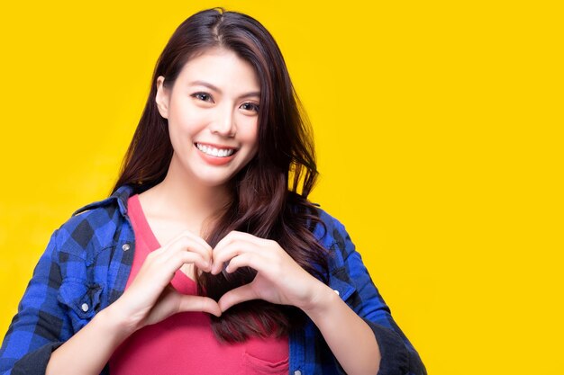Photo portrait of smiling young woman gesturing while standing against yellow background