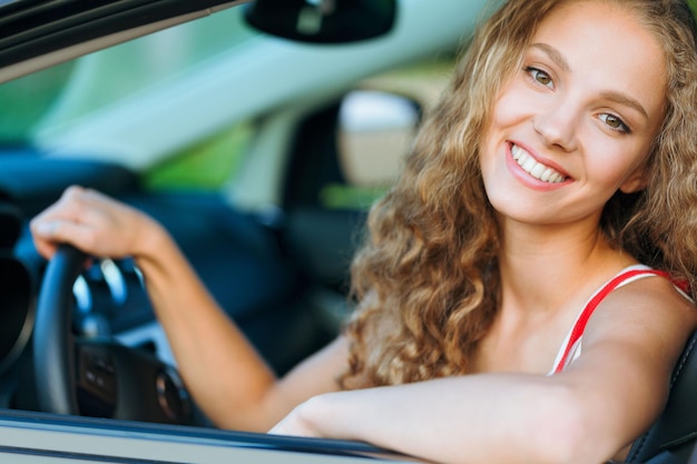 彼女の車の中で笑顔の若い女性の肖像画