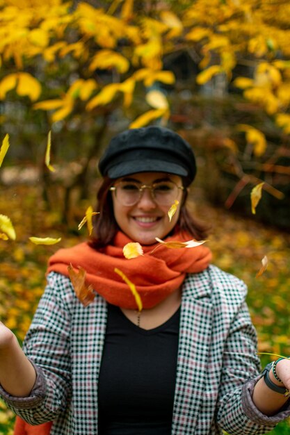 Photo portrait of a smiling young woman holding autumn leaves