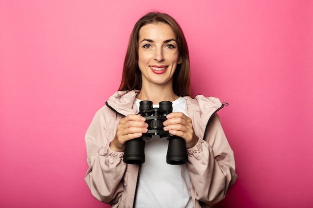 Photo portrait of smiling young woman holding binoculars