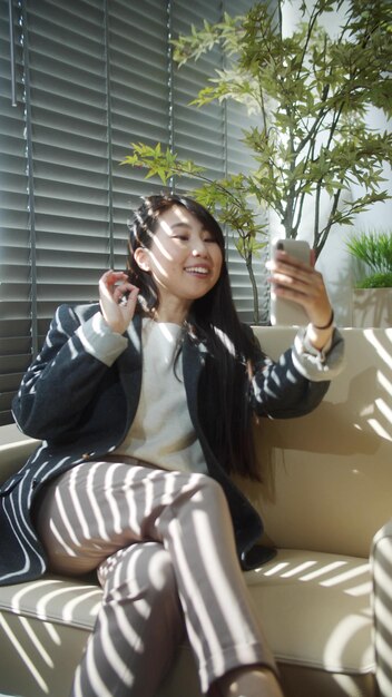 Photo portrait of smiling young woman holding camera while sitting outdoors