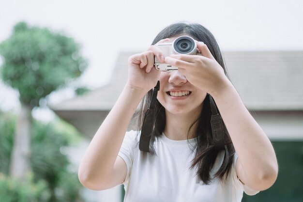 Portrait of smiling young woman holding camera