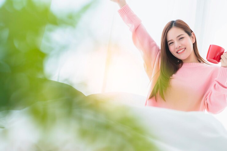 Photo 家でベッドでリラックスしている間コーヒーカップを握っている笑顔の若い女性の肖像画