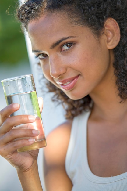 Photo portrait of smiling young woman holding drinking glass