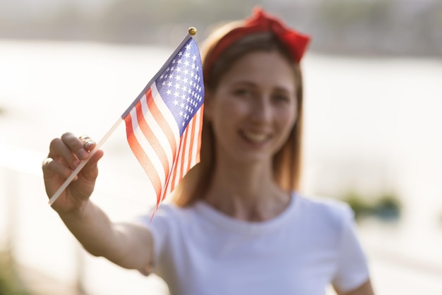Foto ritratto di una giovane donna sorridente che tiene la bandiera