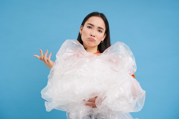 Portrait of smiling young woman holding gift against blue background