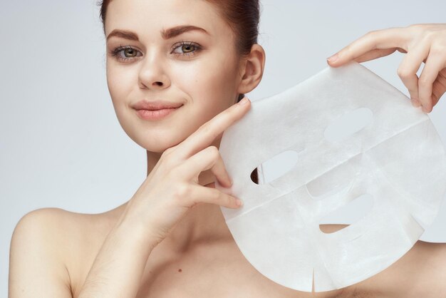 Photo portrait of smiling young woman holding heart shape against white background