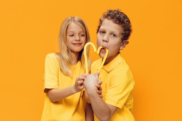 Portrait of smiling young woman holding heart shape against yellow background