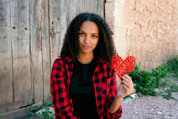 Photo portrait of smiling young woman holding heart shape