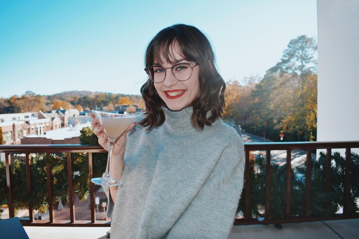 Photo レールに立ってマーティニグラスを握っている笑顔の若い女性の肖像画